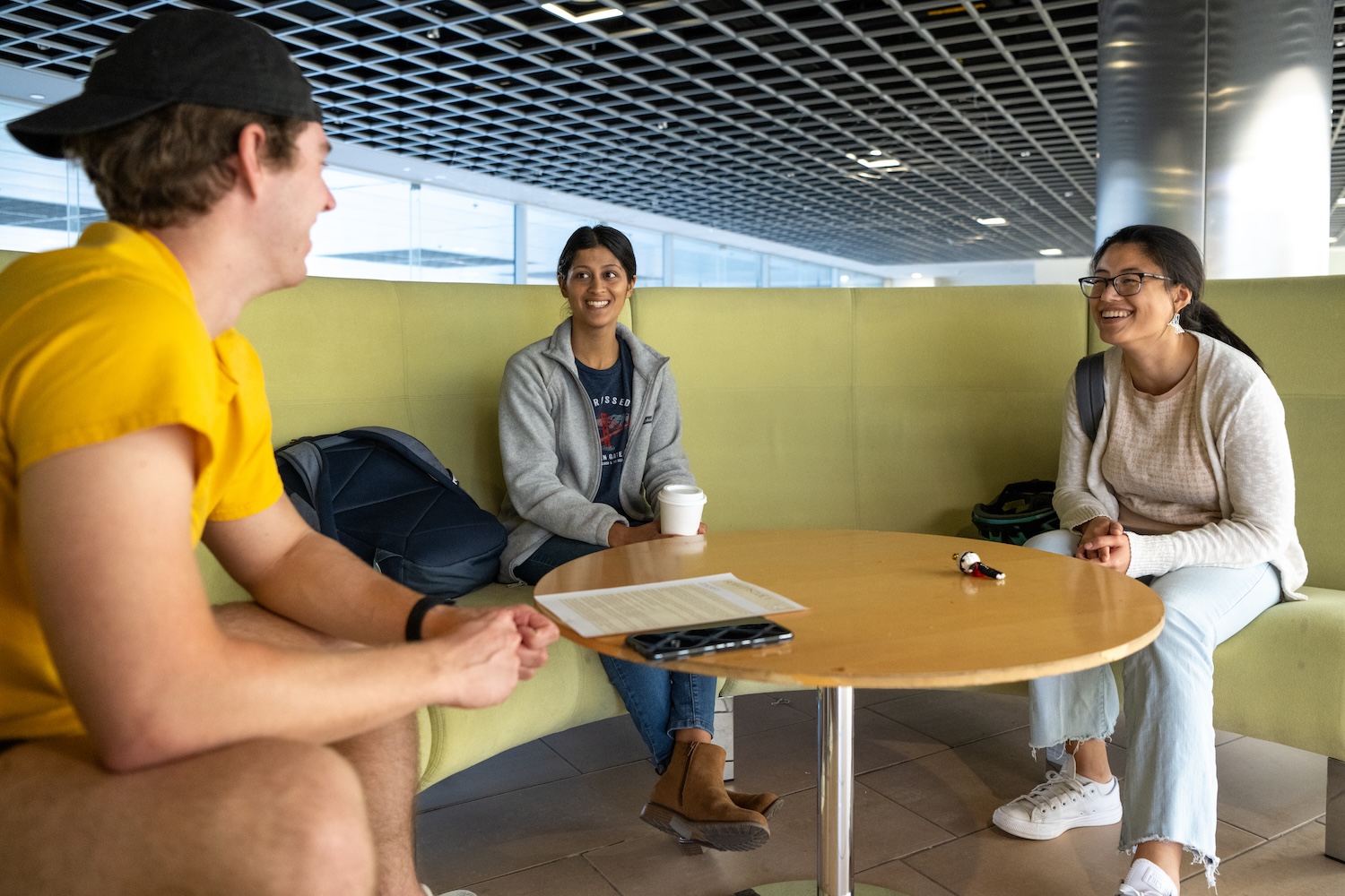 Three people speaking to each other, seated at a round table