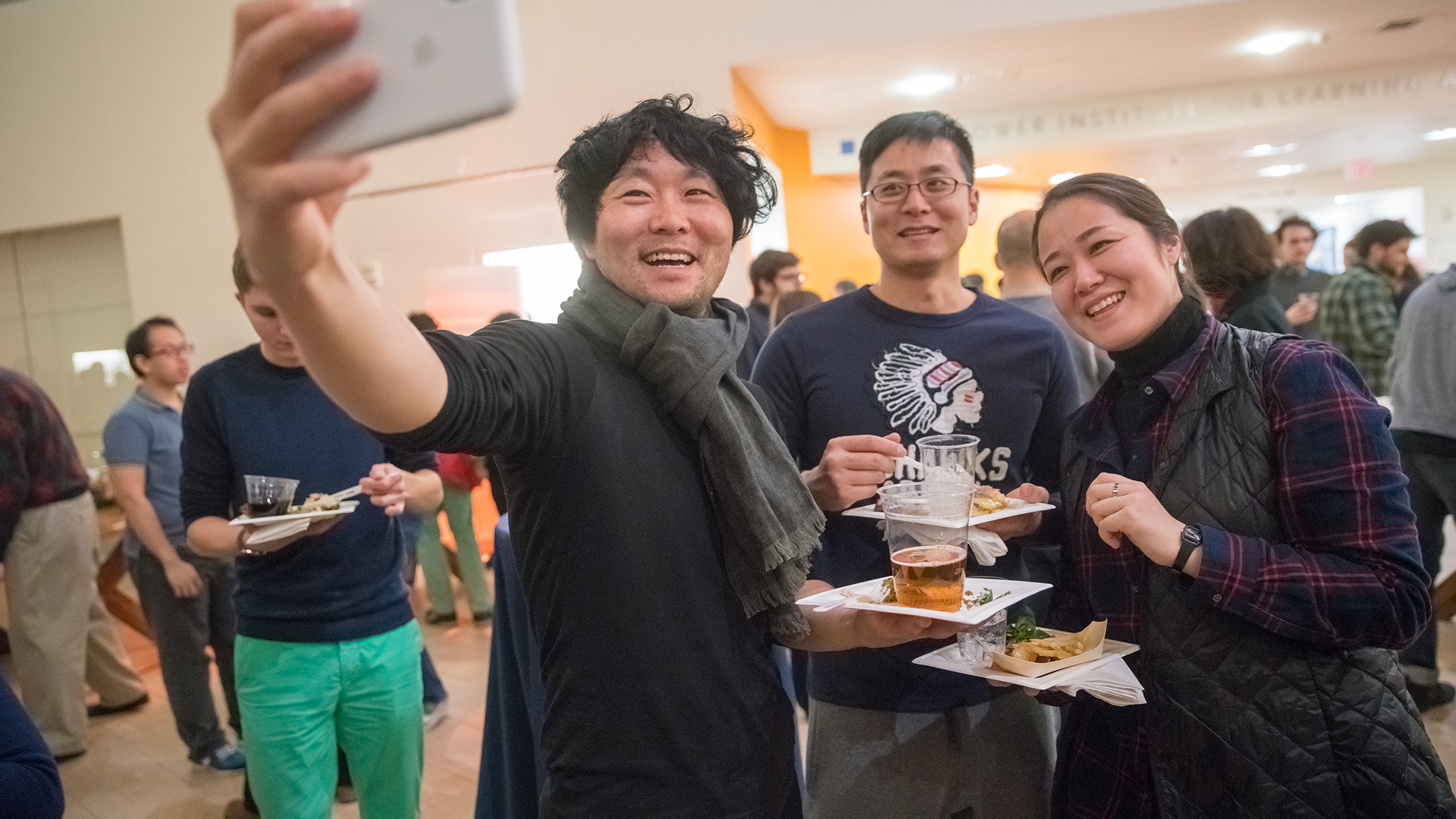 a man takes a selfie of himself and friends at a party